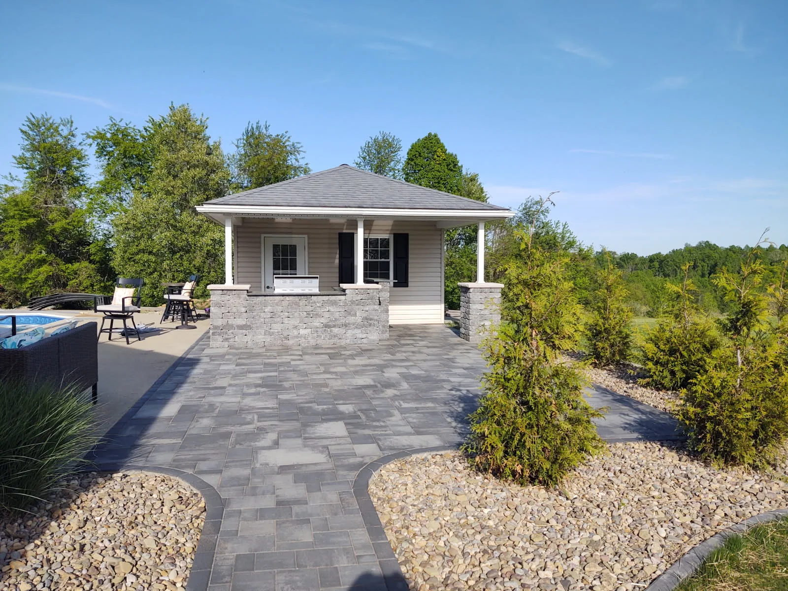 Paver courtyard, poolside pavilion, and planting by Dave's Landscaping